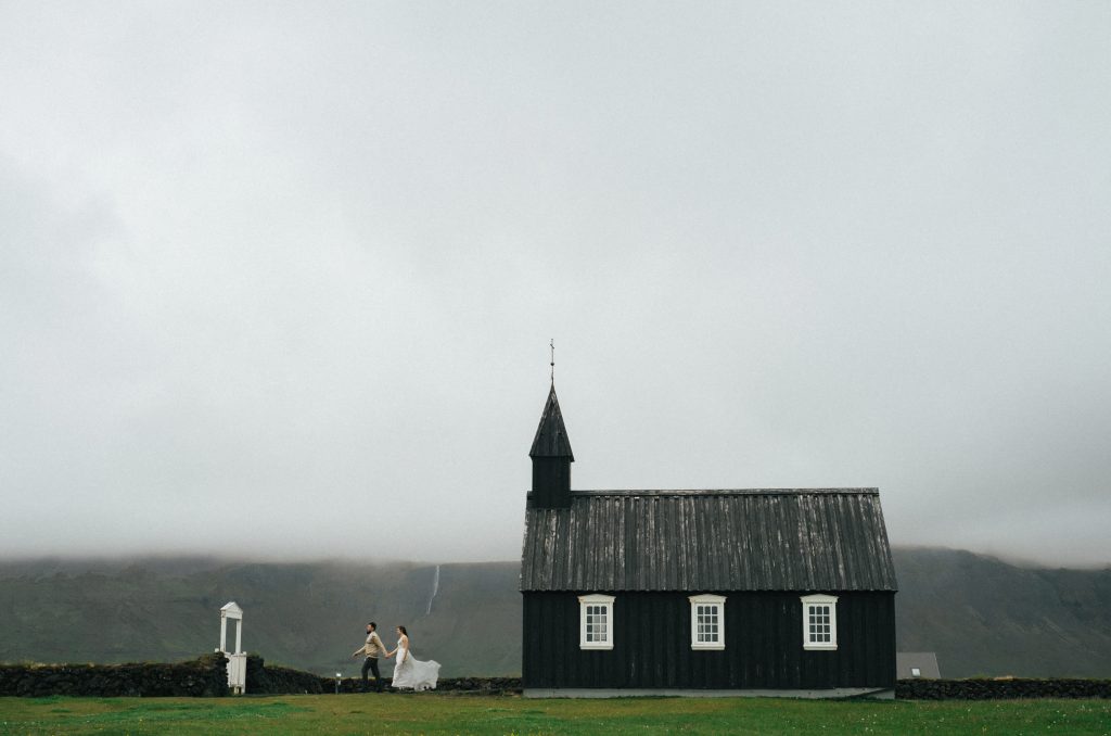 just married couple dashing out of black church with white windows