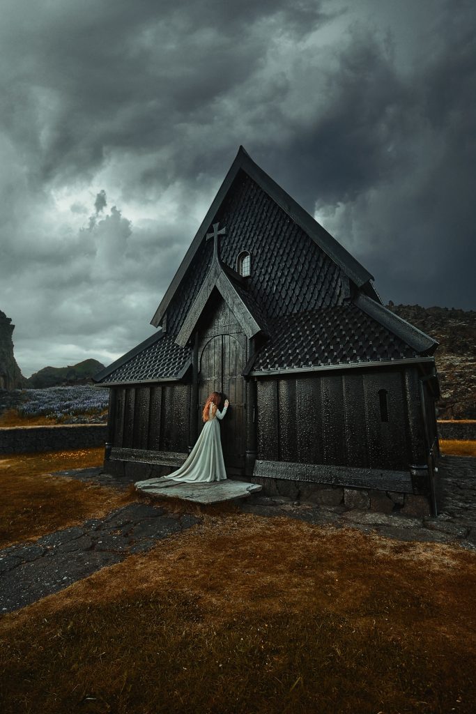 woman weeping against black church on overcast day