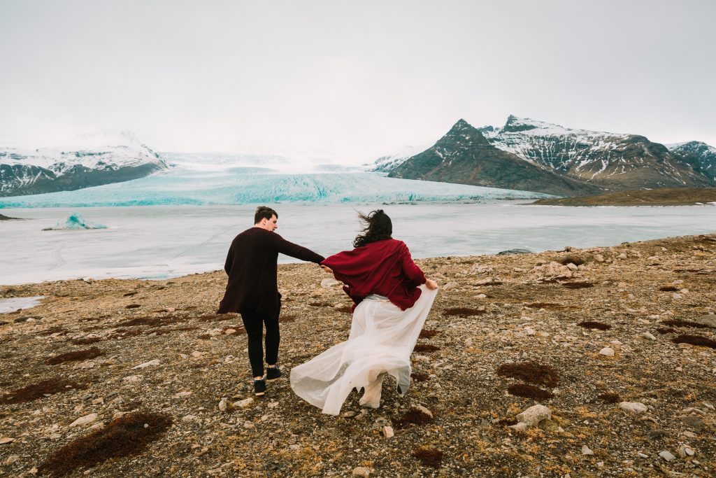 newly married couple running near glacier Iceland wedding