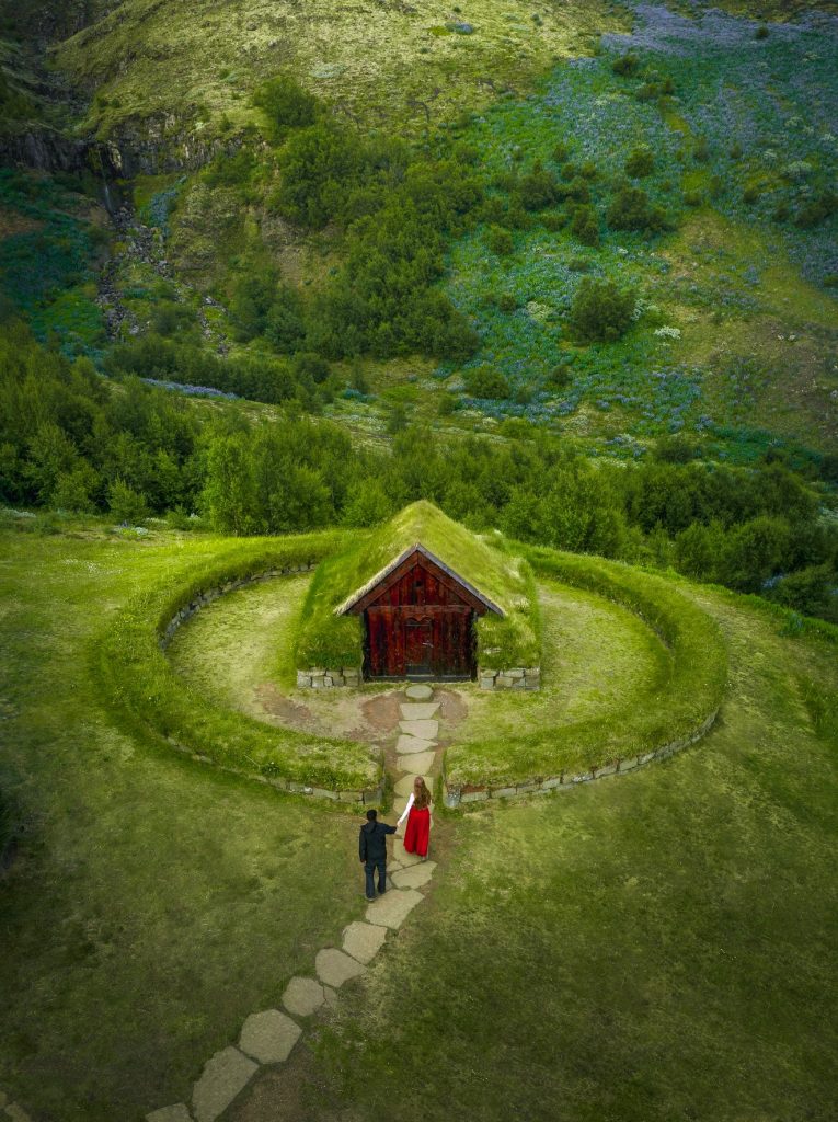 couple walking hand in hand into small, grass roof house Iceland wedding