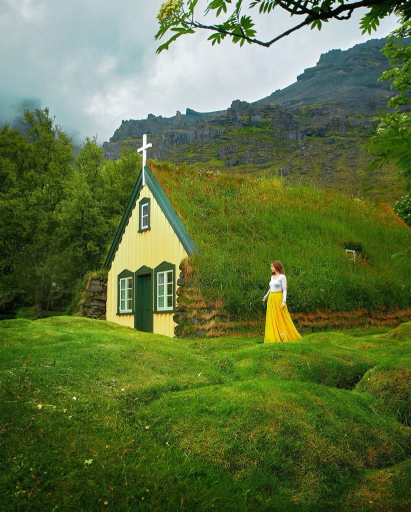 woman standing beside grass roofed church