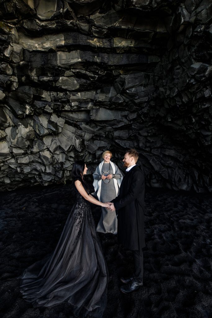 couple being married by female officiant in basalt column cave Iceland wedding