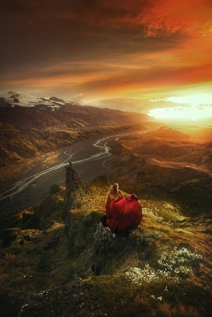 woman in flowing red dress over valley with flowing rivers Iceland wedding