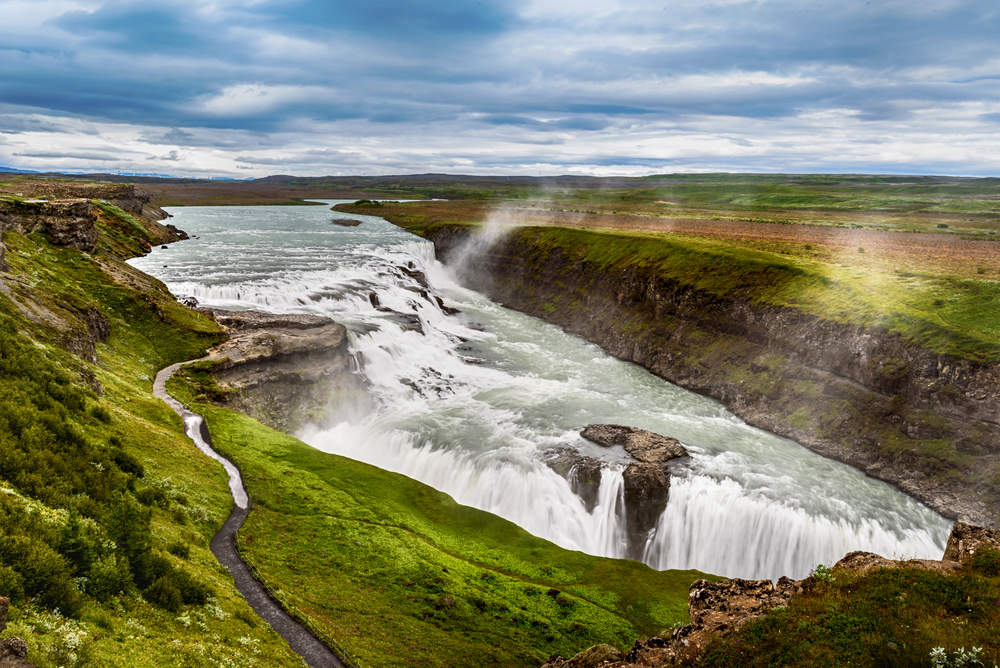 gullfoss waterfall in summer on a cloudy day with green grass all around