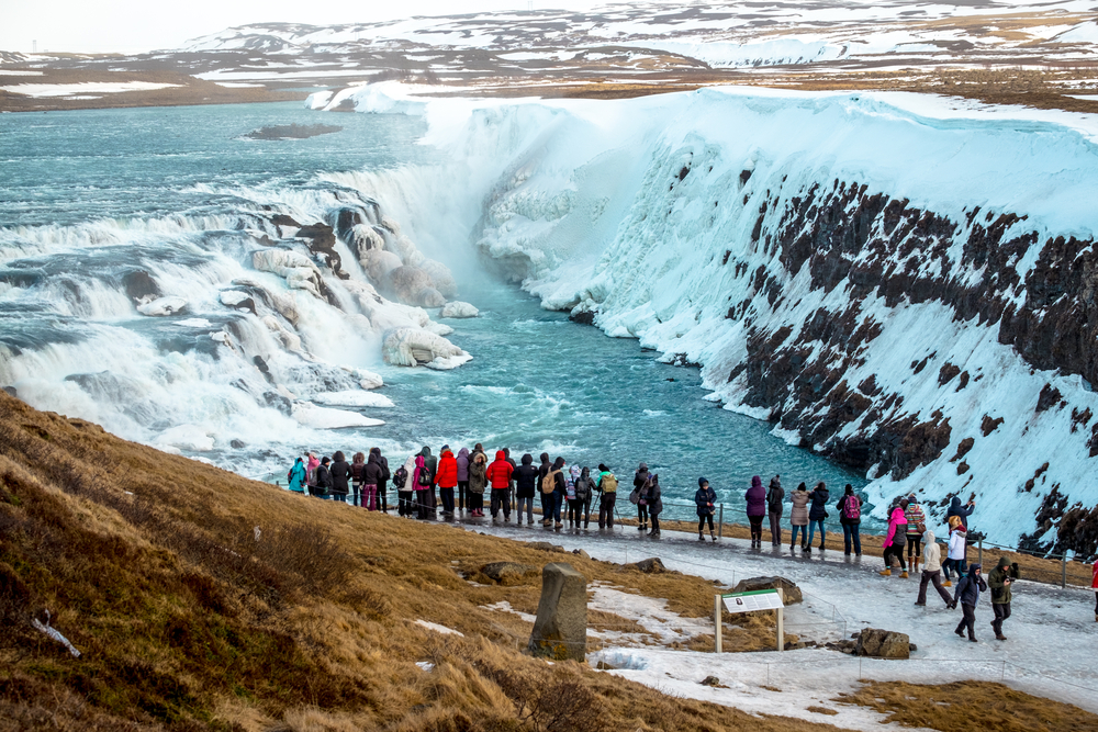 people standing and looking at gullfoss waterfall in winter