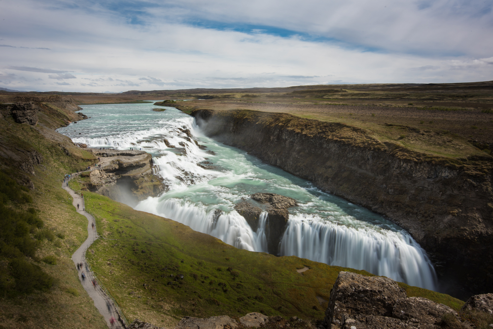 people walking on path at gullfoss in iceland on a sunny day