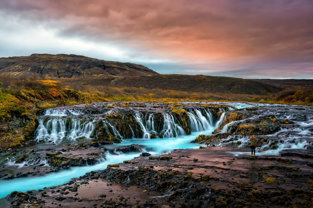 The bright blue water of Bruarfoss against a vivid sunset.