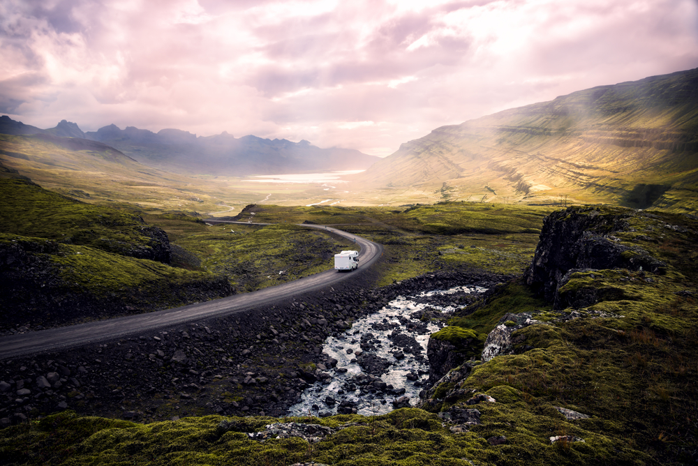 An aerial shot of a campervan in Iceland driving through the mountains.