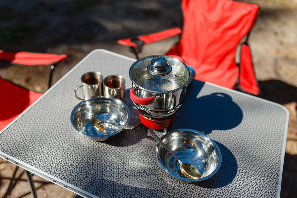 A table with a camp stove and dishes.