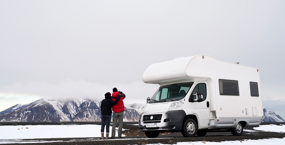 Two people standing next to a motorhome in Iceland in a snowy landscape.