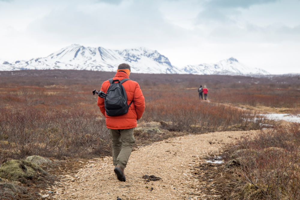 A man hiking the trail to Bruarfoss Waterfall. with mountains in the distance.