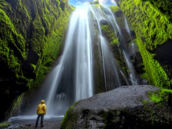 man in yellow jacket standing in hidden waterfall in Iceland on 3 day itinerary
