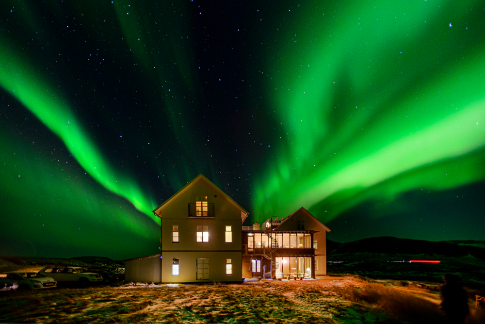 Hotel in iceland lit up at night with northern lights in the sky