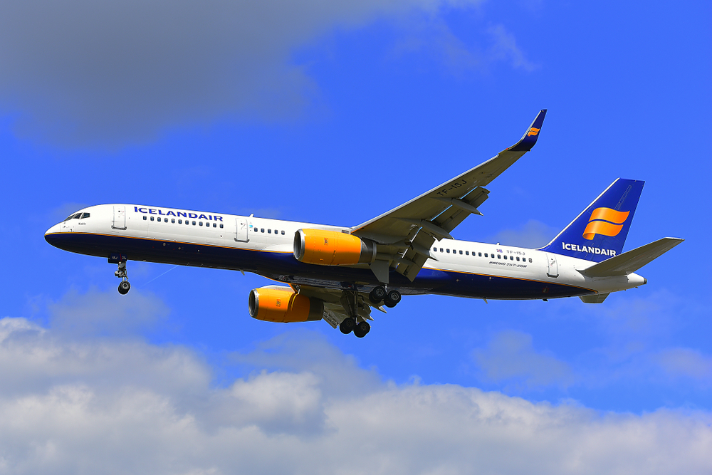 Icelandair airplane flying over head on clear day with blue skies and clouds