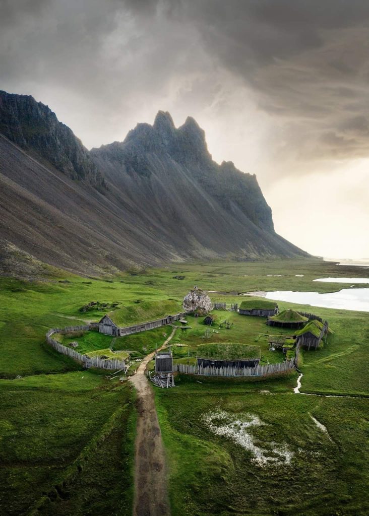 Aerial shot of small fake Viking village with mountains in background one of the best secret places in iceland