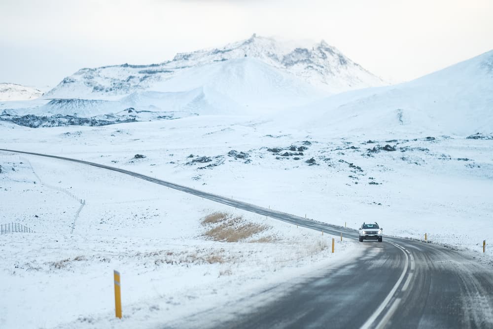 car driving on a road towards the camera on a moody snowy winter day