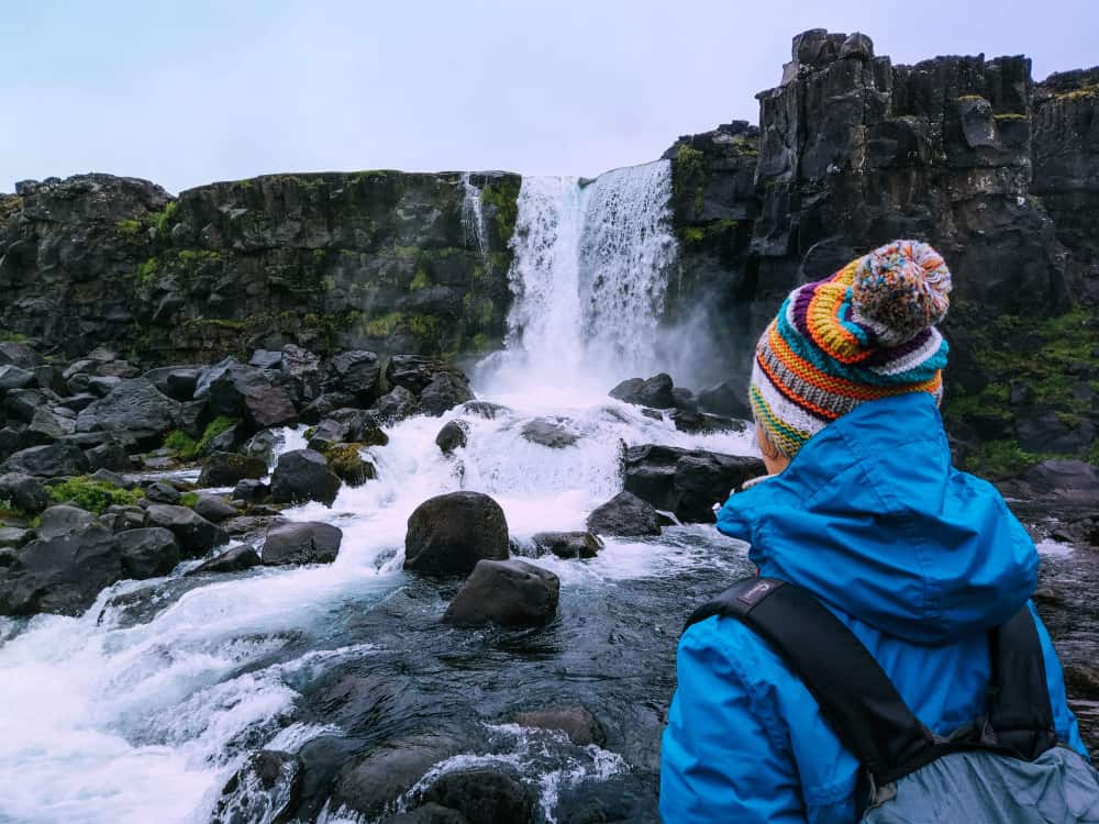 person standing in front of waterfall in iceland in november