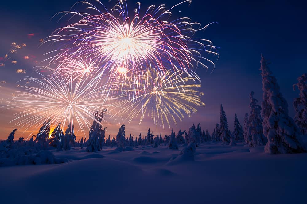 fireworks for New Years Eve with snow covered trees at twilight 