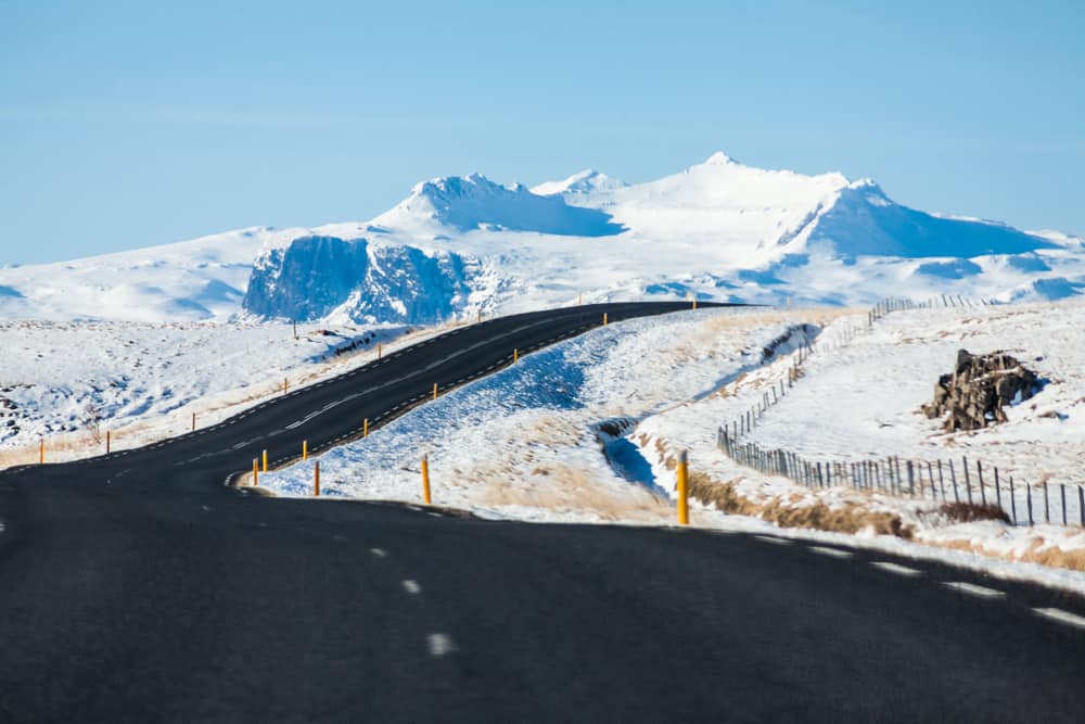 a smooth clean asphalt road with snow on the side of the road on a sunny winter day