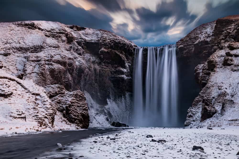 Skogafoss waterfall in Iceland on a moody winter day with snow on the ground