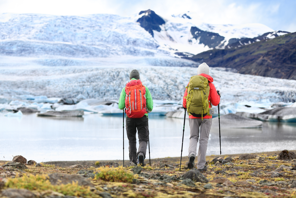 tourists in cold weather clothes and hiking gear near the glacier lagoon