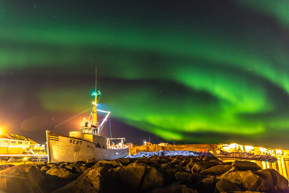 Northern Lights in Reykjavik over a boat in the harbor