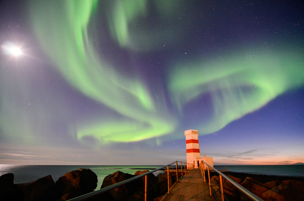 Northern Lights swirling above one of the lighthouses in Gardur