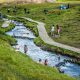 people swimming in Reykjadalur Hot Springs thermal river in iceland with green grass