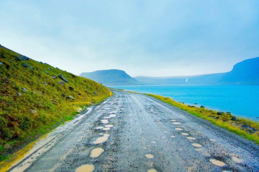 road with pot holes on a moody day in iceland in the WestFjords