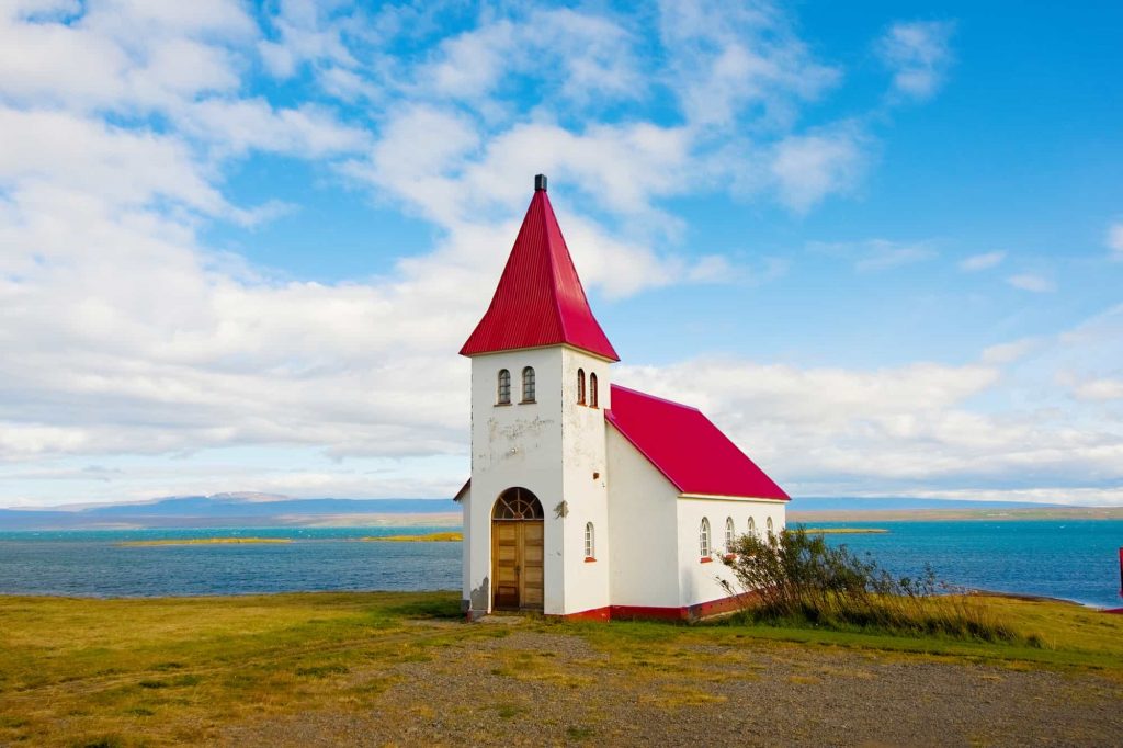 Cute little red church in iceland on a sunny day with blue skies