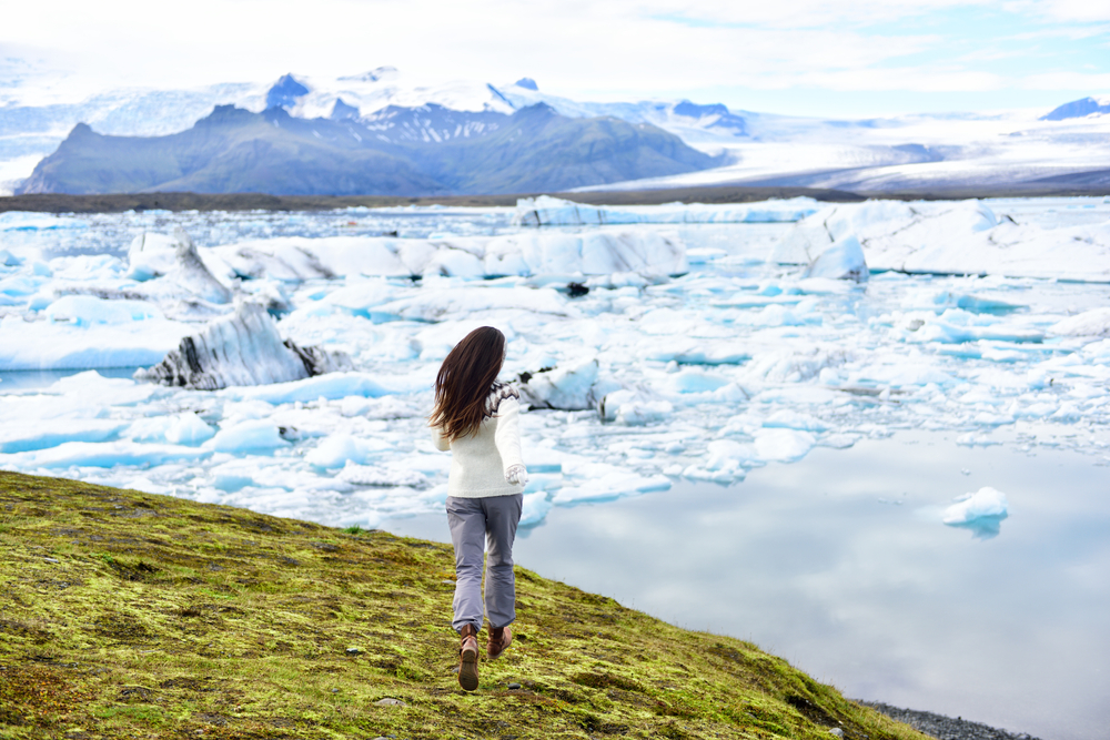woman standing in front of glaciers showing off what to wear in iceland in winter