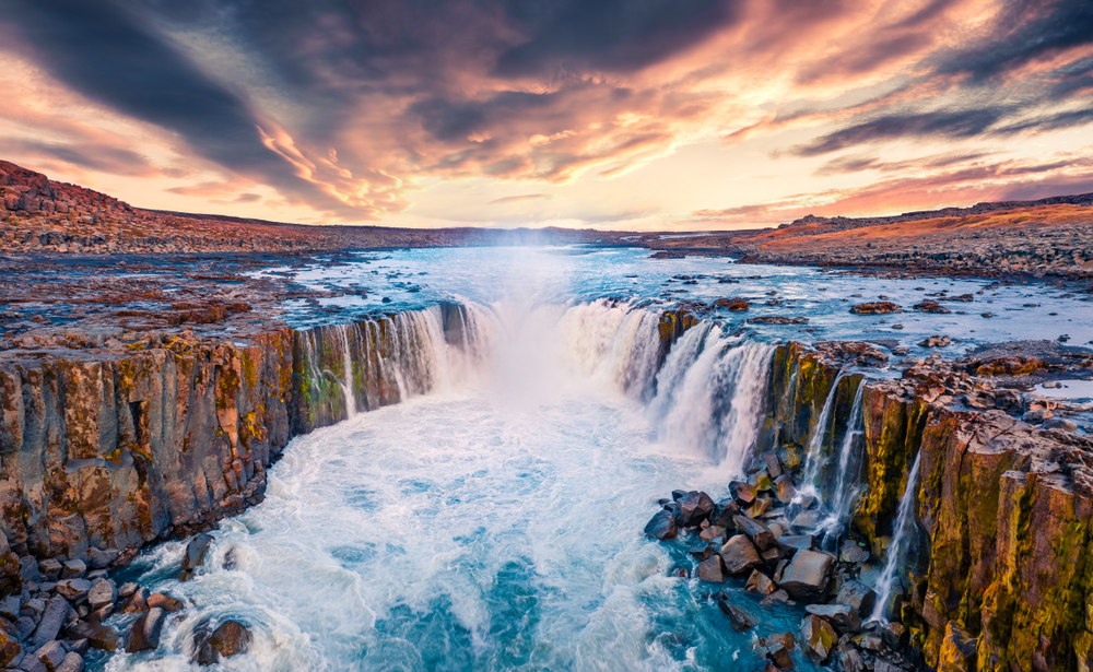 Selfoss Waterfall in Jokulsargljufur Canyon with multiple waterfalls flowing into river below at sunset