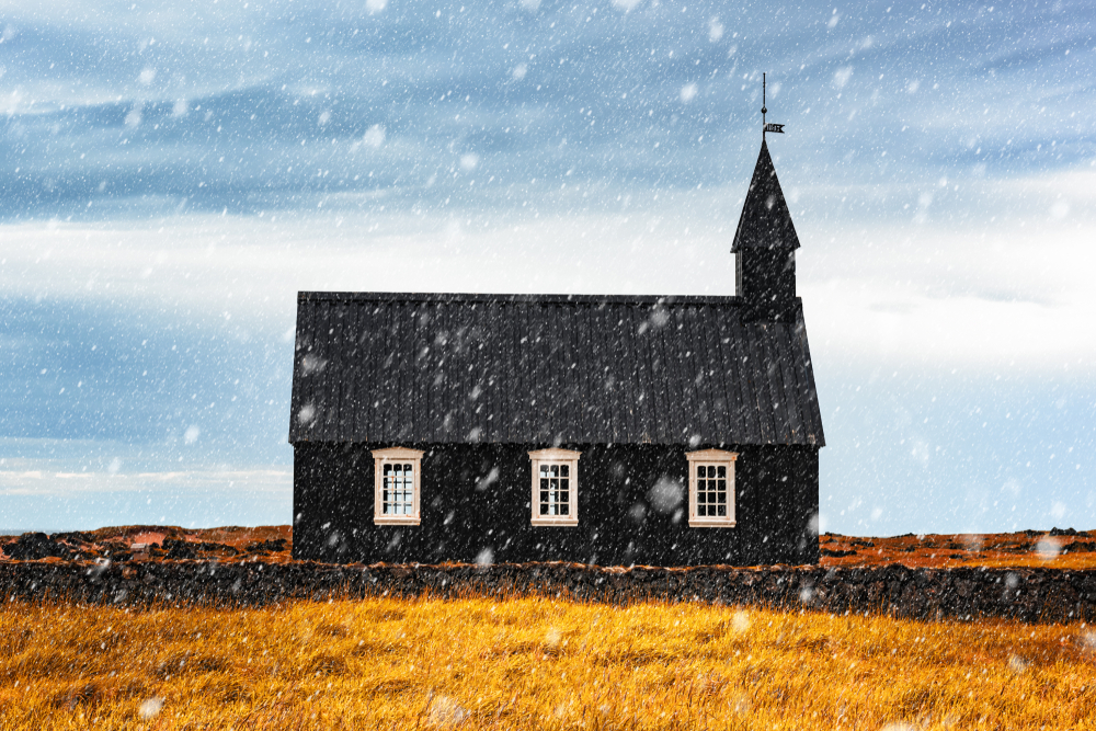The black Budir Church with snow falling.