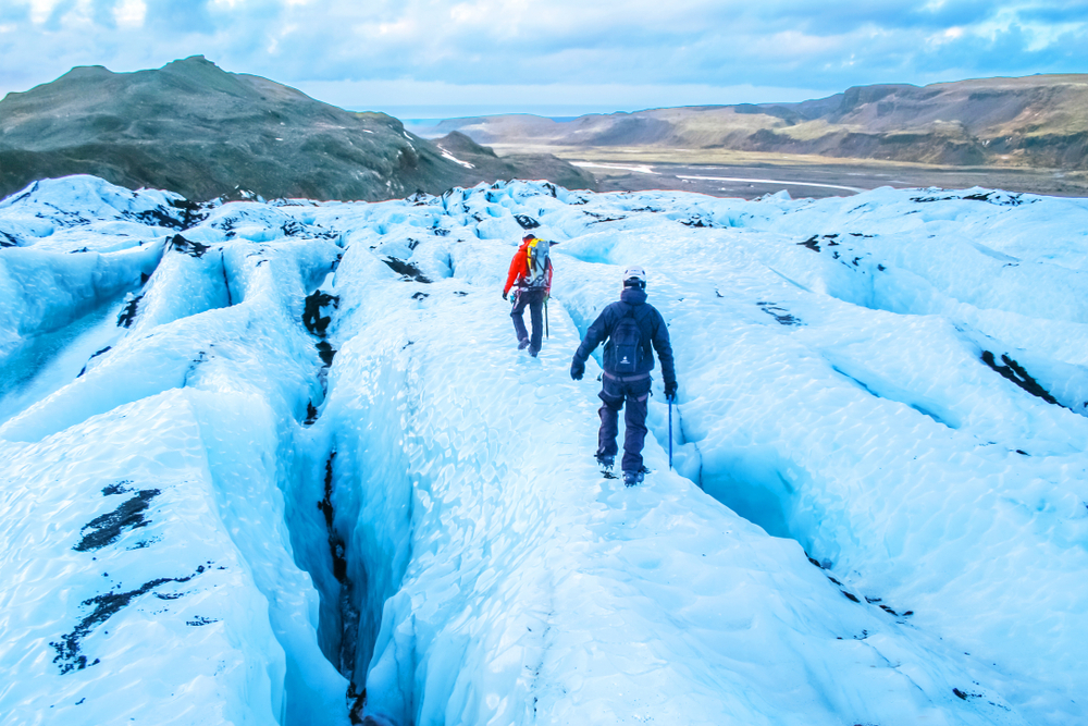 Two people hiking over a glacier in Iceland. This is a must-do Iceland winter activity.