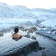 person relaxing in hot spring in iceland during winter
