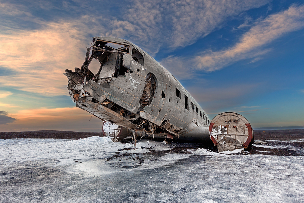 The broken shell of the Solheimasandur plane wreck with a colorful sky and snow on the ground.