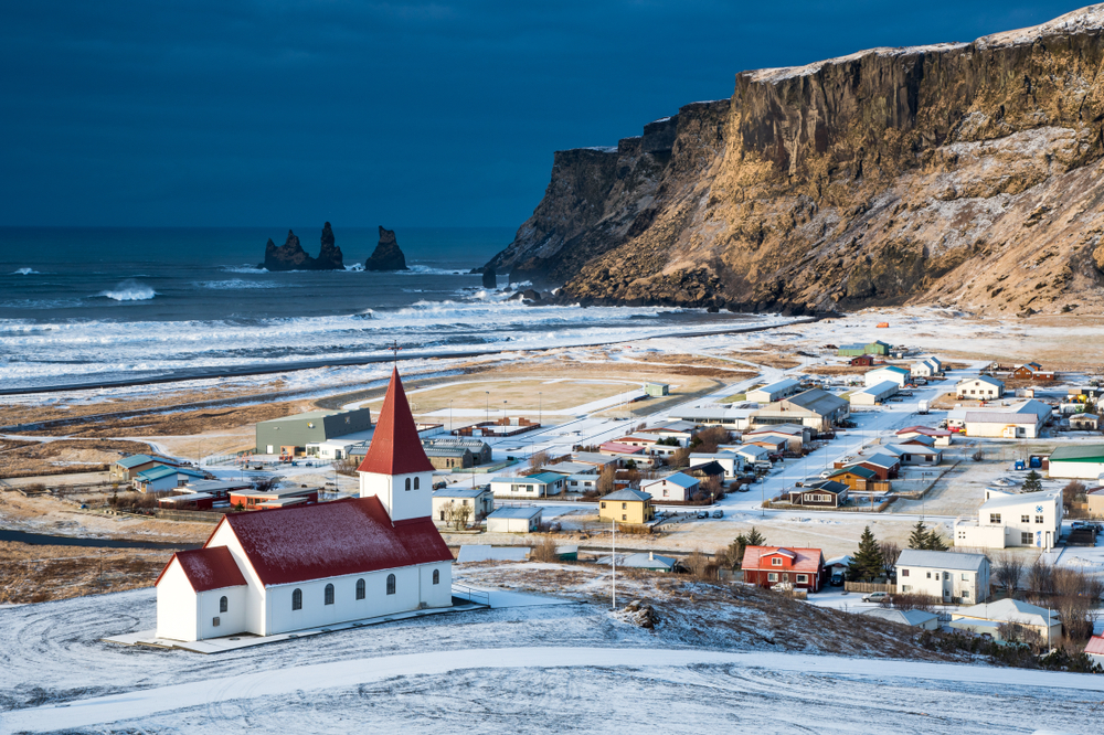 Vik covered in snow and the ocean in the distance.