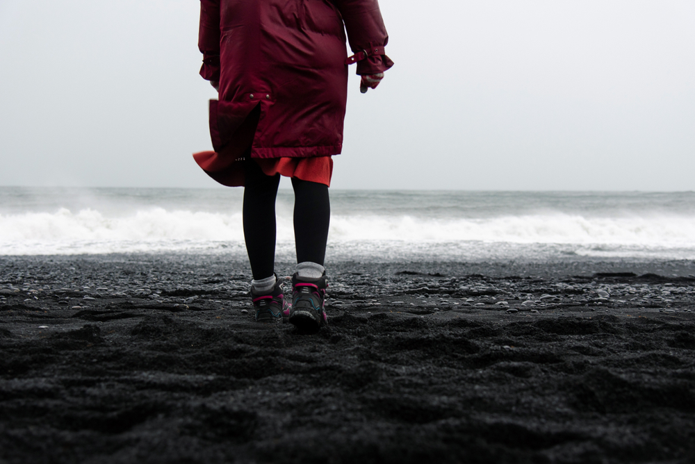 woman in hiking boots in iceland on a black sand beach