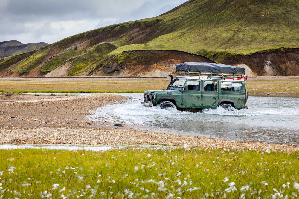 a 4WD car driving through the river in the highlands of Iceland