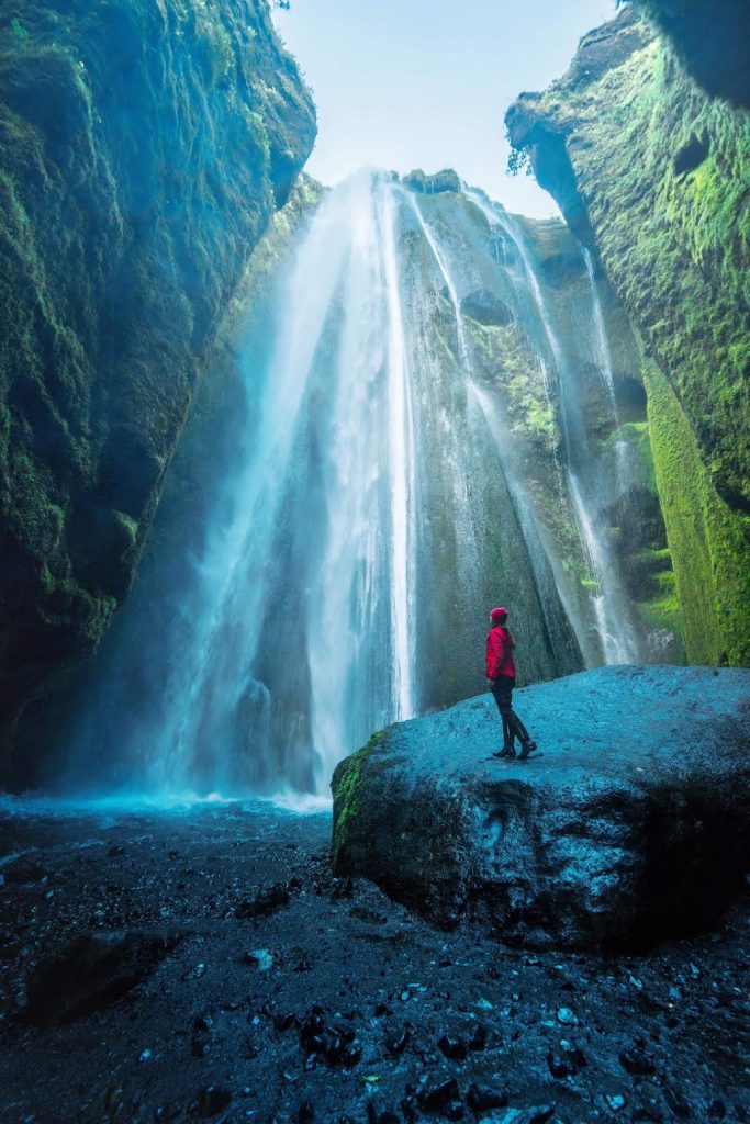 standing on a rock and looking up at Gljufrabui waterfall