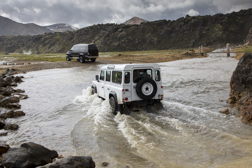 A 4x4 vehicle crossing a river in Iceland's highlands.