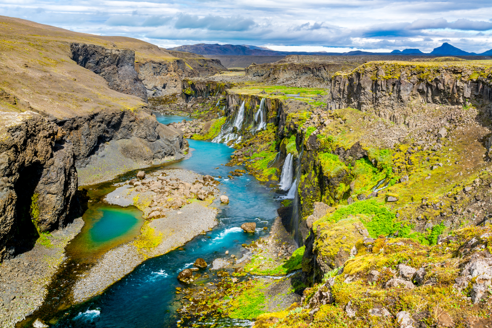 Waterfalls falling into the Sigoldugljufur canyon and a bright, blue river.