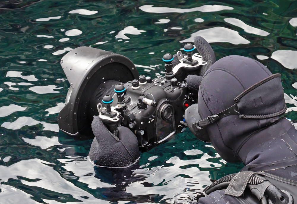 A diver with a camera, ready to take photos of other people snorkeling silfra in iceland