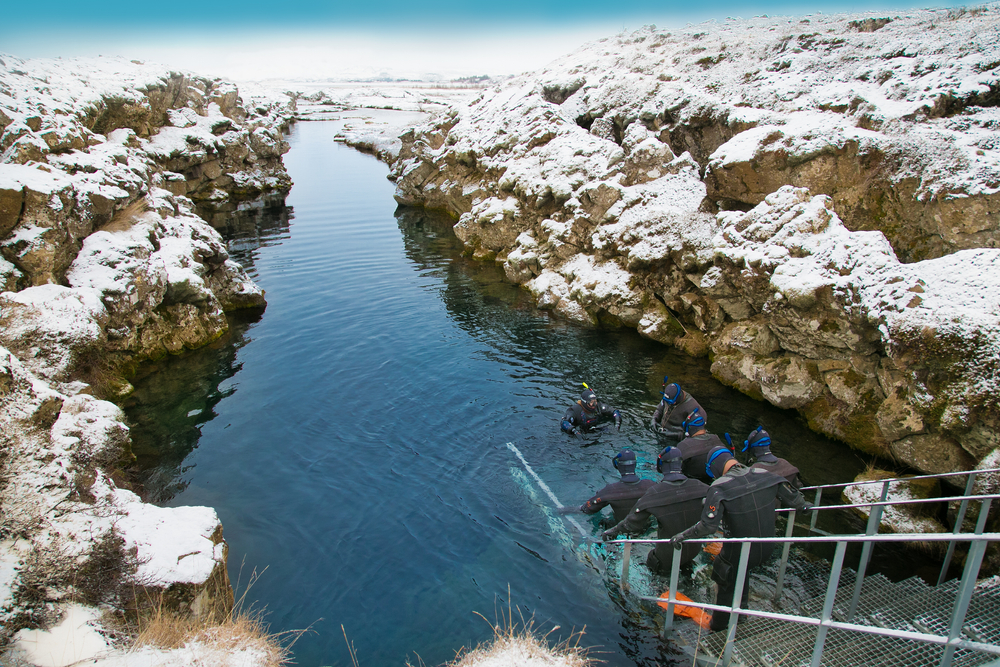 Ice and snow capped land surrounds the fissure as divers get ready for their tour at the Silfra landing.