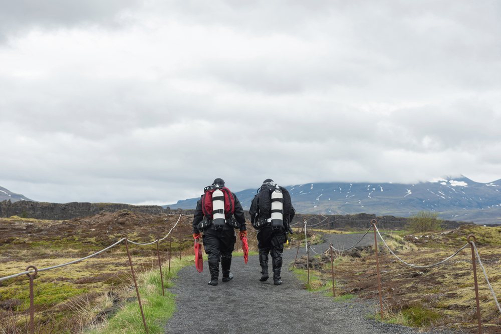 Two divers walk on a path toward the Silfra fissure in iceland