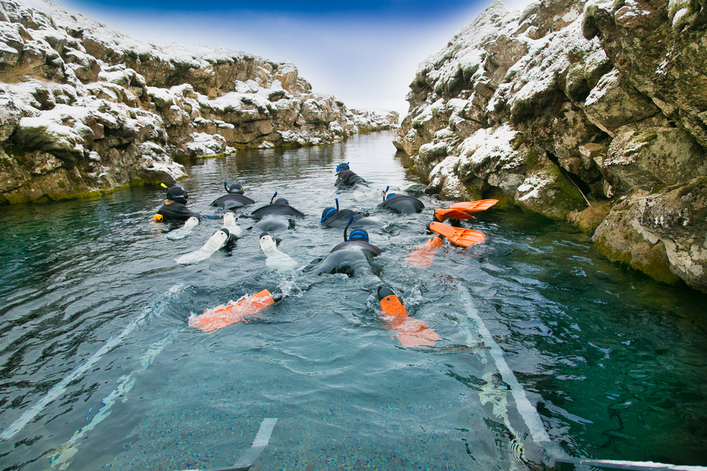 Silfra fissure Snorkelers with orange fins float through a fissure.