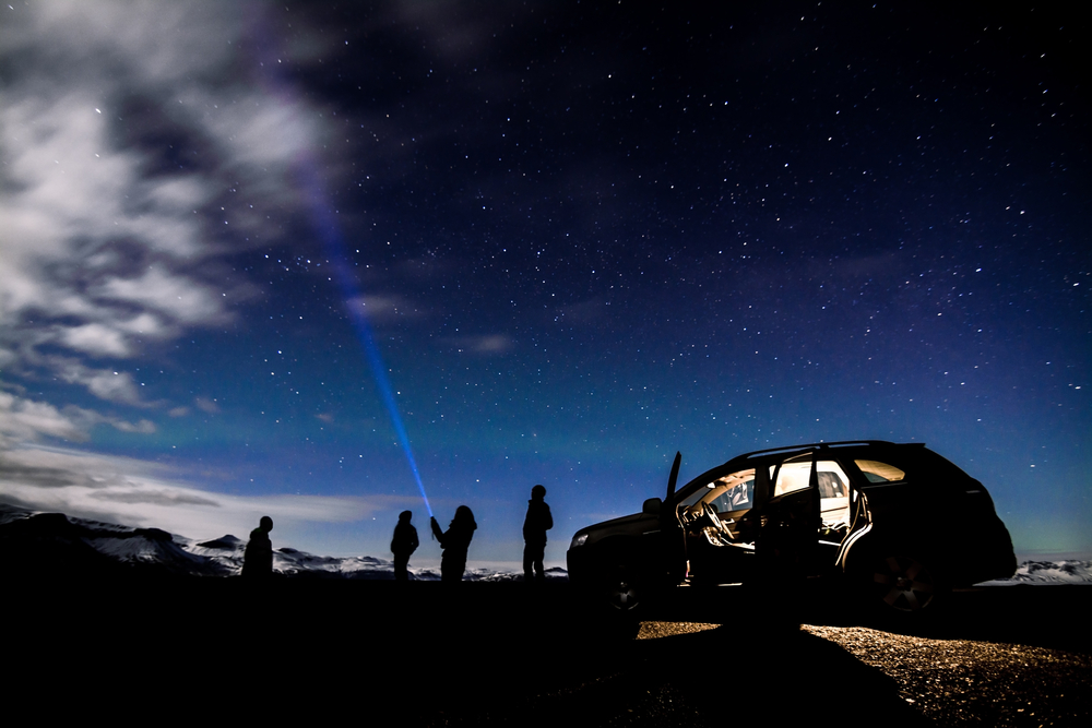 A group of people search the night Iceland sky for stars with lights