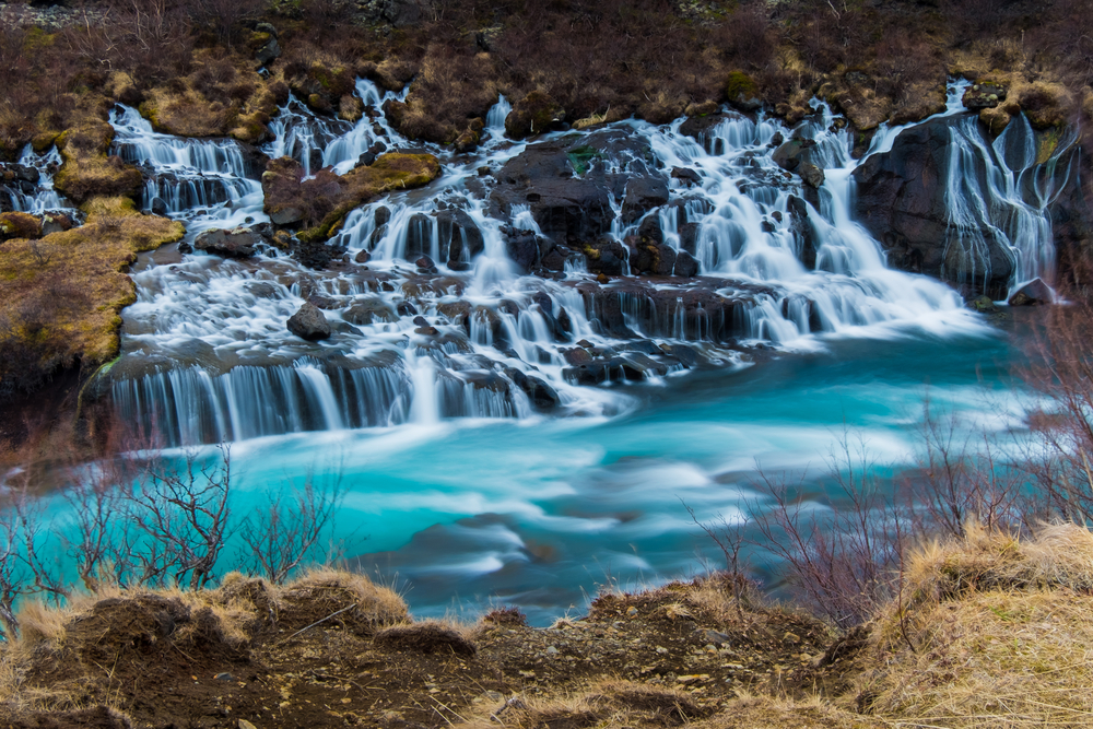 The icy blue waters of Barnafoss cascade down dark rocks
