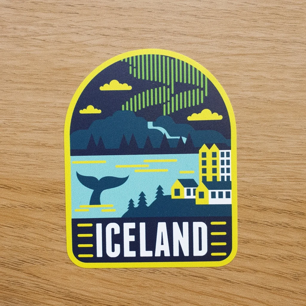 An Iceland decal that features a mountain, a whale tail, some city, and the northern lights in colors of yellow and blue.