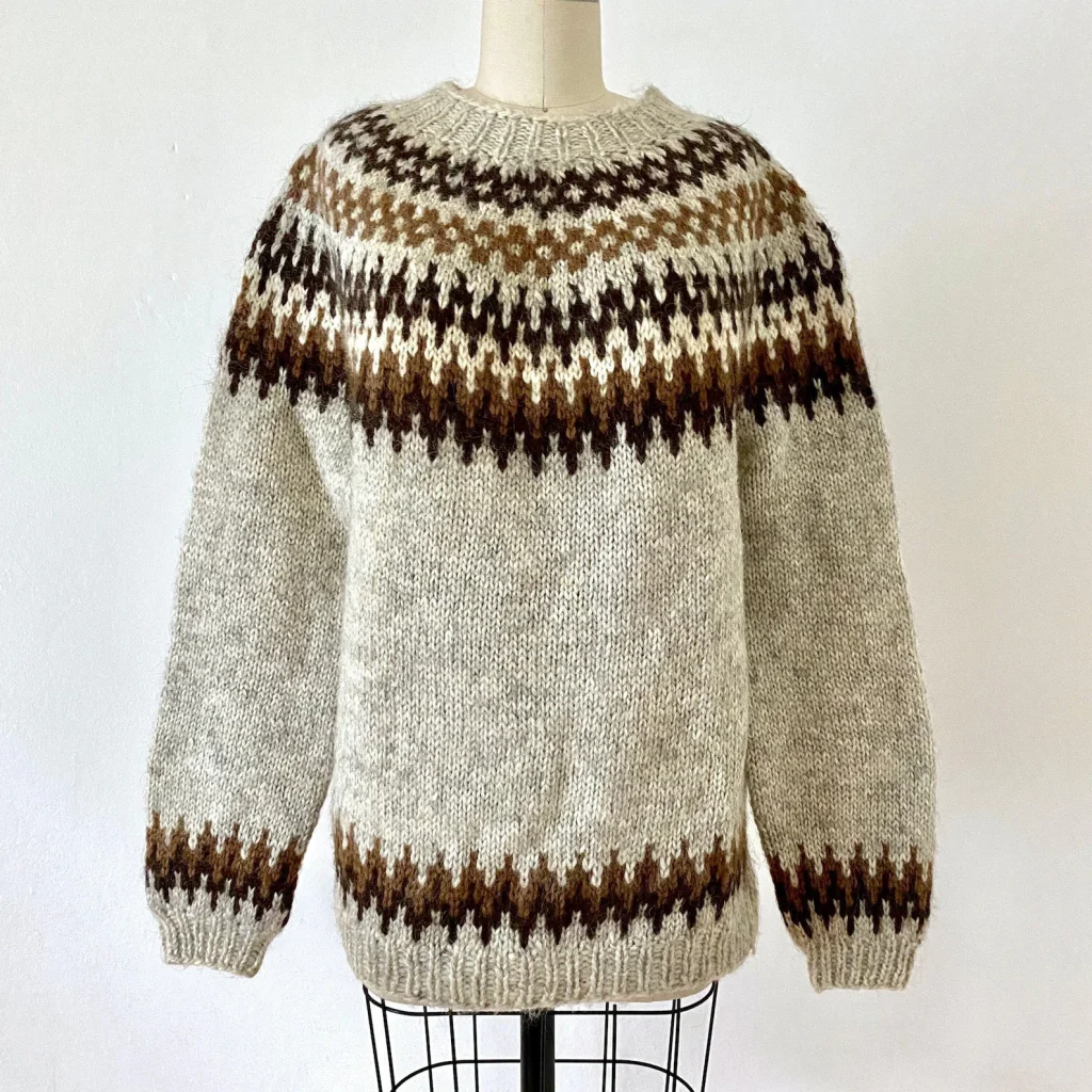 A wool sweater that is light brown and features dark brown designs around the collar and hem.